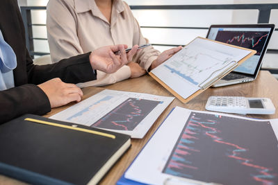 Midsection of business people working on table