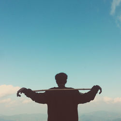 Rear view of man standing against blue sky