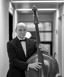 Portrait of smiling mature men playing double bass at hallway