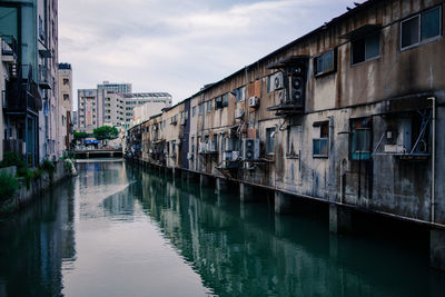 Canal amidst buildings in city against sky