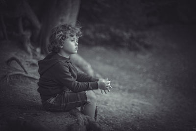 Side view of boy looking away while sitting on land