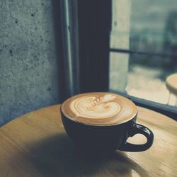 Close-up of coffee cup on table by window at restaurant