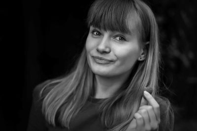 Close-up portrait of smiling teenage girl eating raspberry against black background