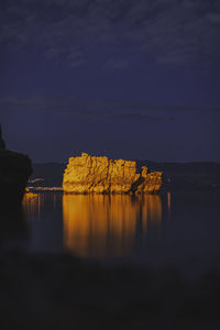 Reflection of rock formation in sea against sky at night