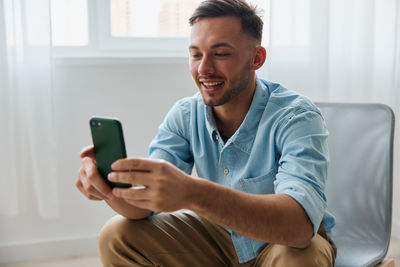 Young man using mobile phone while sitting at home