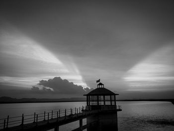 Silhouette pier over sea against sky during sunset