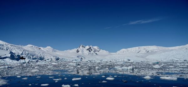 Scenic view of snowcapped mountains against blue sky