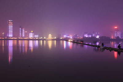 Illuminated skyline reflecting on river at night