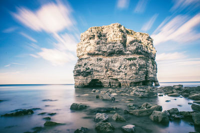 Rock formation in sea against sky