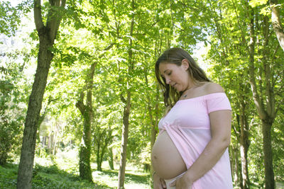 Side view of woman standing against trees