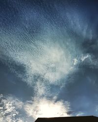 Low angle view of sunlight streaming through clouds