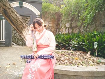 Young woman in kimono sitting at park