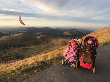 Cute siblings sitting in baby carriage on road