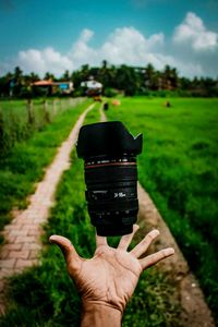 Cropped hand catching lens on grassy field