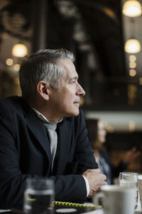 Businessman looking away while leaning on table during seminar