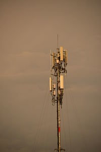 Low angle view of communications tower against sky during sunset