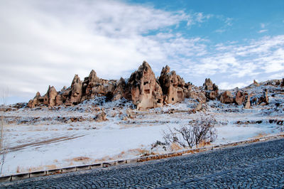 Rock formations on snow covered land against sky