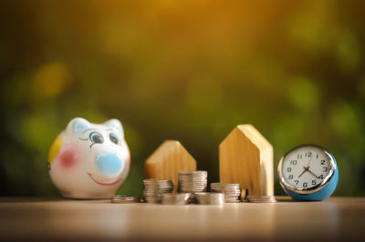 Stack of coins and mode houses by piggy bank on table