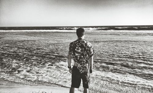 Rear view of a man overlooking calm sea