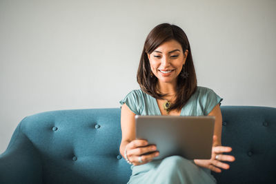 Latin woman on a video call sitting on the furniture in her house. copy space.