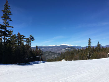 Scenic view of snow covered mountains against blue sky