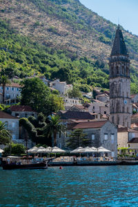 Sea by buildings in town against mountain