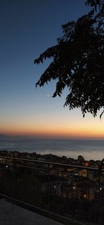 Silhouette tree by sea against sky at sunset