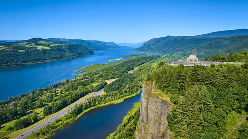 Scenic view of sea and mountains against clear blue sky