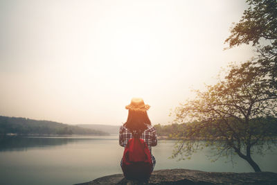 Man standing by lake against sky during sunset