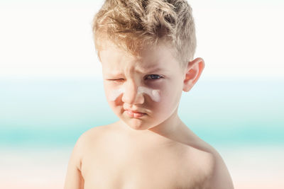 Close-up portrait of shirtless boy against sea