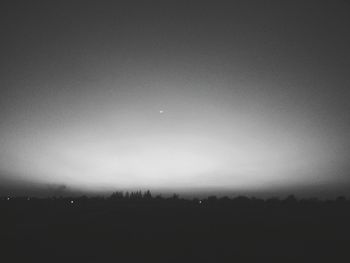 Silhouette trees against clear sky at night