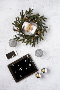 Directly above shot of digital tablet and mobile with christmas decoration on snowy field