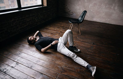 High angle view of young man lying on hardwood floor