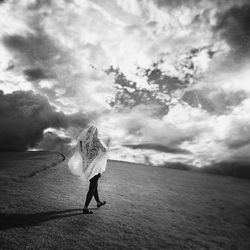 Woman standing against cloudy sky