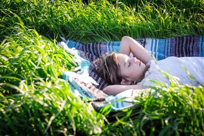 High angle view of girl sleeping on blanket amidst plants
