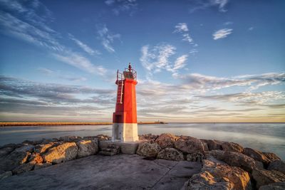 Lighthouse by sea against sky