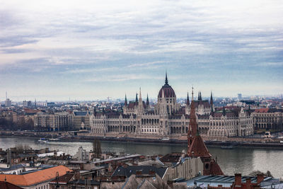 View of buildings in city against cloudy sky