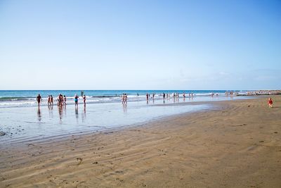 People on beach against clear sky