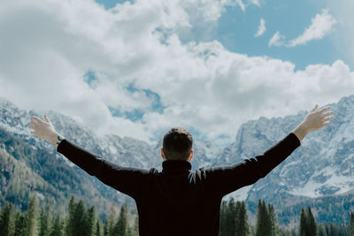 Rear view of hiker with arms outstretched against dramatic sky