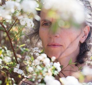 Close-up portrait of young woman with flowers on tree