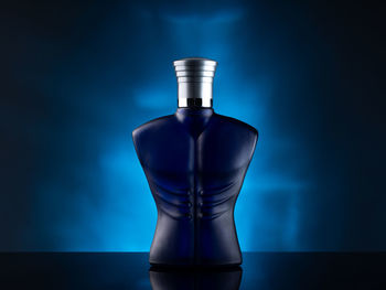 Close-up of perfume bottle on table against blue background