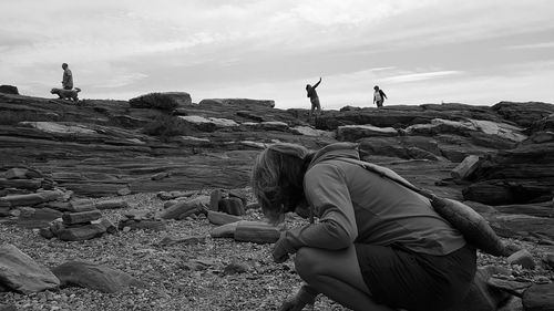 Woman standing on rock against sky