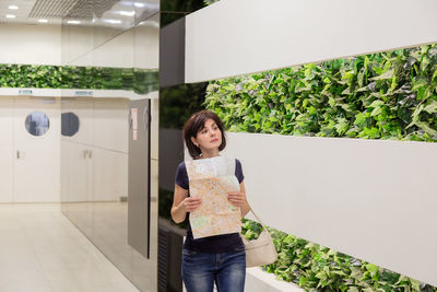 Portrait of young woman standing against building