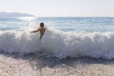 Little kid enjoying the waves on myrtos beach, greece.