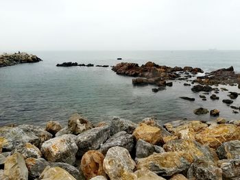 Rocks on sea shore against sky