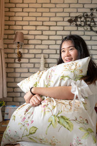 Portrait of a smiling young woman sitting against wall