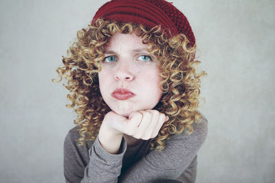 Portrait of displeased young woman puffing cheeks against gray background