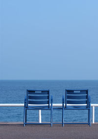 Deck chairs on beach against clear blue sky