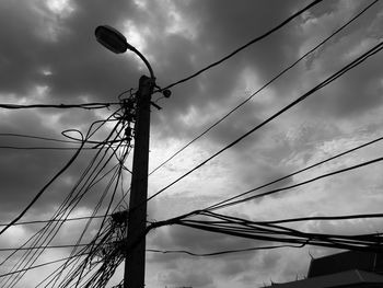 Low angle view of silhouette electricity pylon against sky