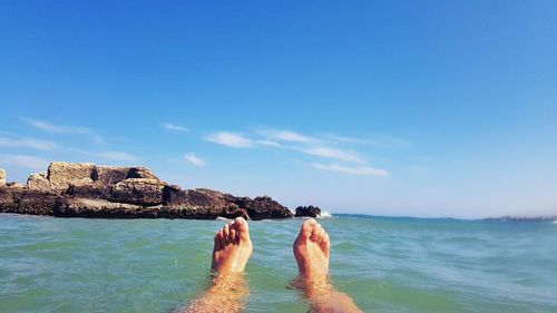 Low section of man in sea against sky